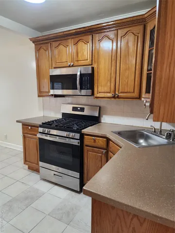 a kitchen with stainless steel appliances granite countertop a stove a sink and a microwave