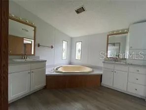 a spacious bathroom with a double vanity sink a mirror and a bathtub