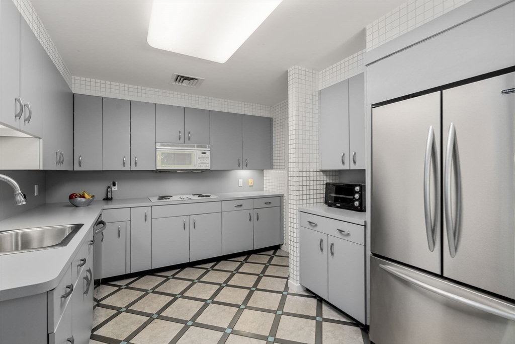 228 Allandale Road, Unit 1B Boston, MA 02467 - Photo 10 of 30 a kitchen with granite countertop white cabinets and white appliances