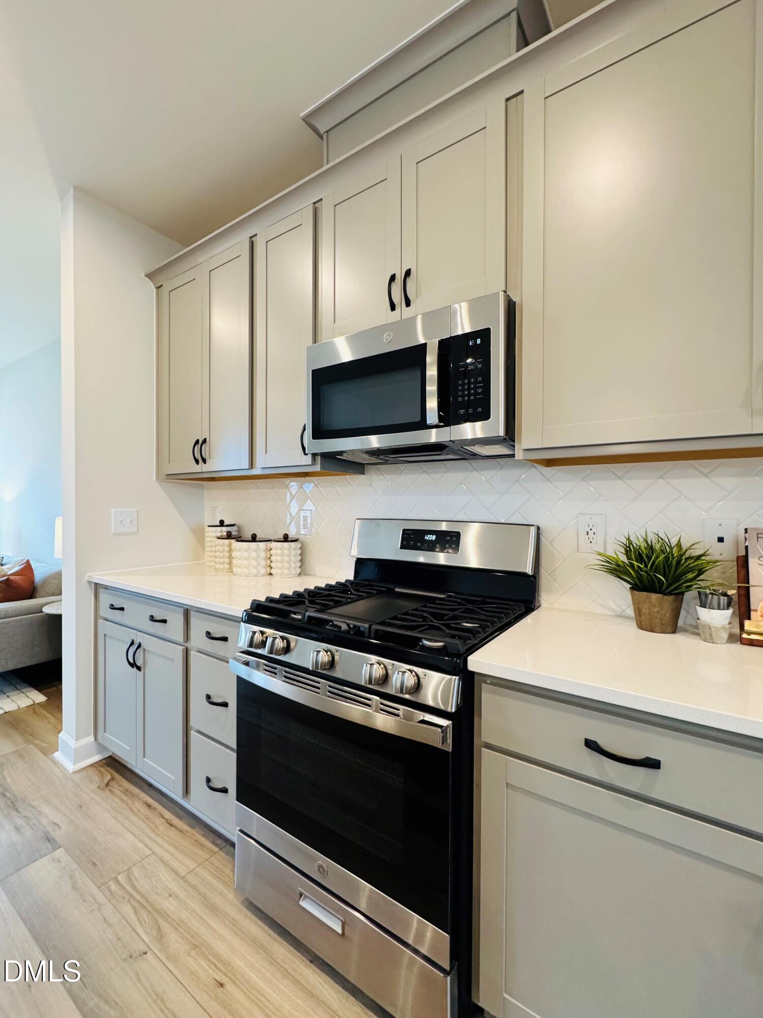 706 Hyperion Alley Wake Forest, NC 27587 - Photo 11 of 67 a kitchen with stainless steel appliances a stove a microwave and cabinets