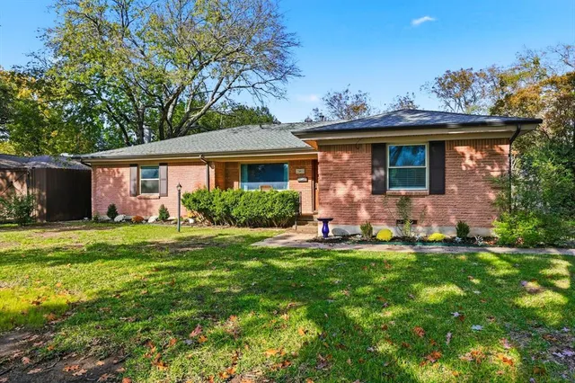 a front view of a house with a yard and trees