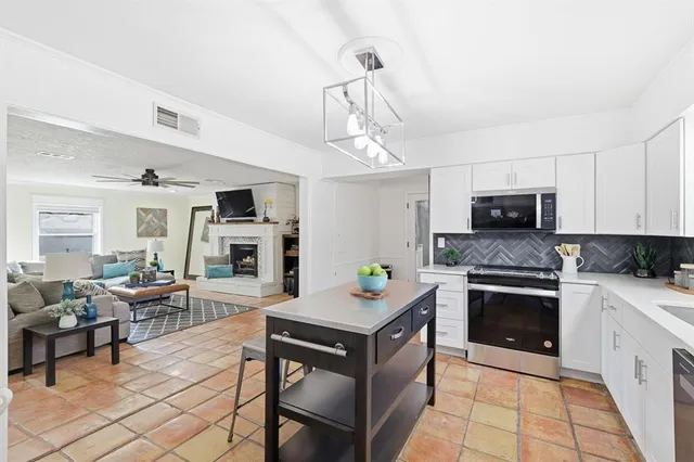 a kitchen with stainless steel appliances granite countertop a stove top oven a sink dishwasher a dining table and chairs with wooden floor