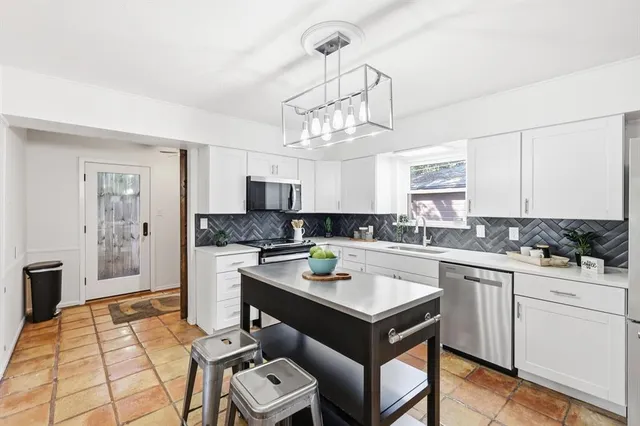 a kitchen with a sink dishwasher a stove a microwave oven and a dining table with wooden floor