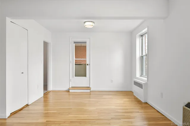 a view of an empty room with wooden floor and a window