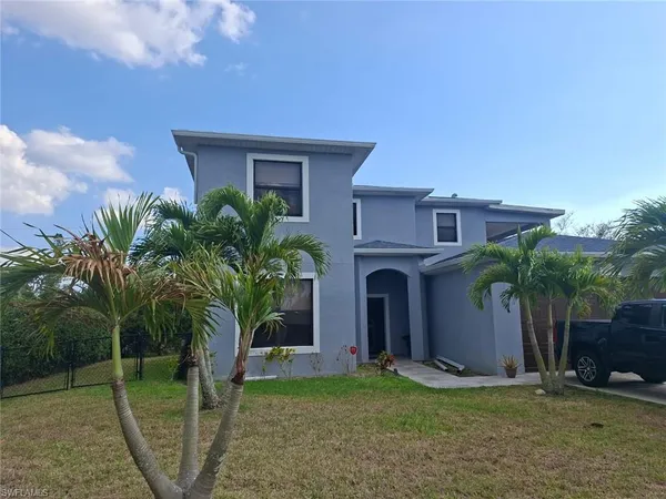 a view of a house with a yard and palm trees