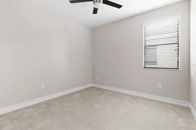 an empty room with a window and a ceiling fan