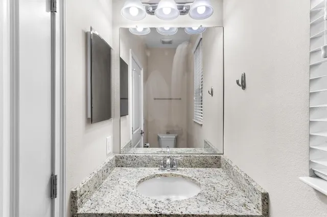 a bathroom with a granite countertop sink a mirror and shower