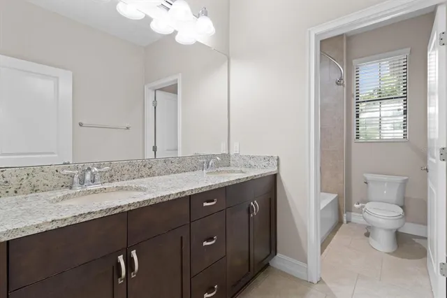 a bathroom with a granite countertop sink a toilet and a mirror
