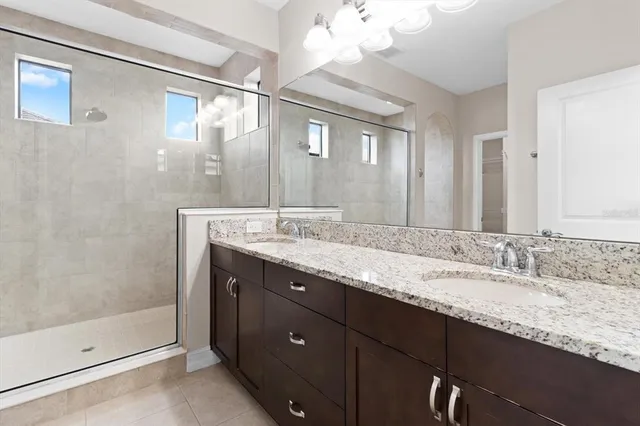 a bathroom with a granite countertop sink a mirror and shower