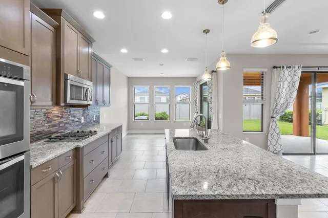 a large kitchen with kitchen island granite countertop a large window and stainless steel appliances