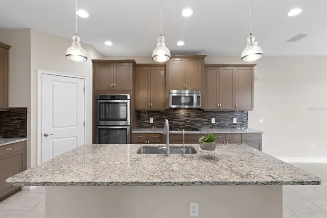 a kitchen with stainless steel appliances granite countertop a sink a stove and a microwave