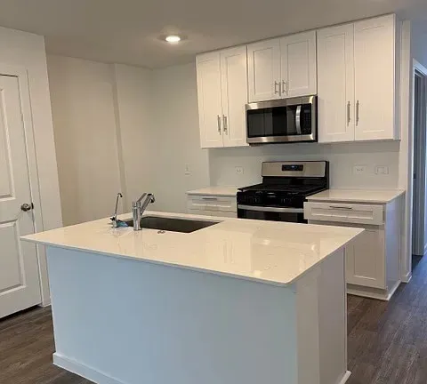 a kitchen with stainless steel appliances a sink a stove a microwave and white cabinets