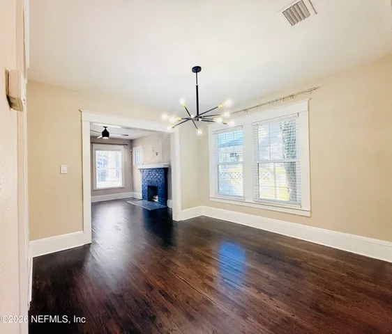 a view of a livingroom with wooden floor a ceiling fan and kitchen space