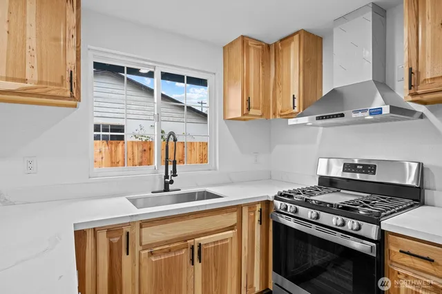 a kitchen with granite countertop a sink stainless steel appliances wooden floor and a window