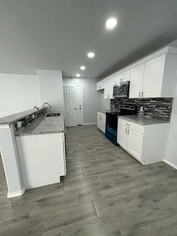 a kitchen with stainless steel appliances granite countertop a stove a sink and a microwave