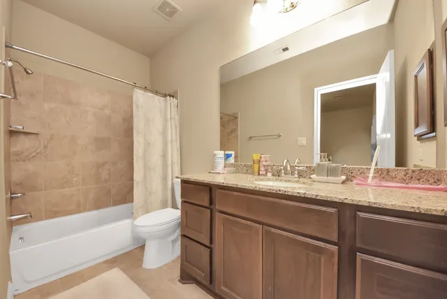a bathroom with a granite countertop sink toilet mirror and bathtub