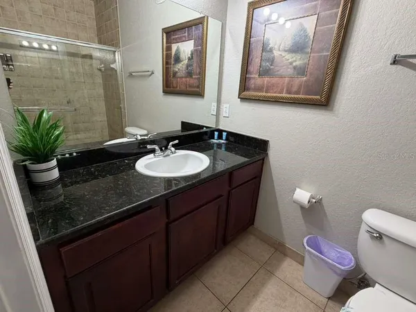 a bathroom with a granite countertop sink a mirror and a toilet