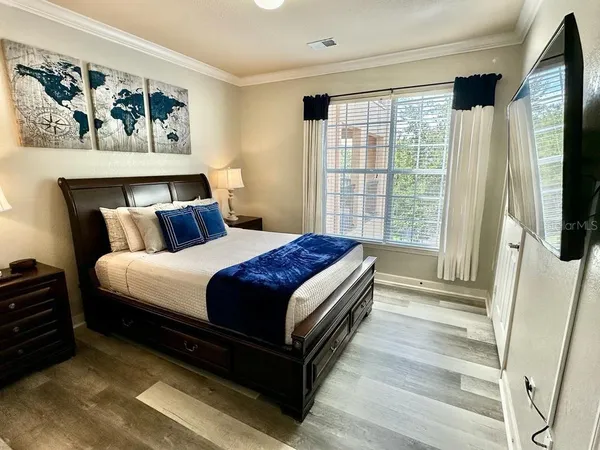 a bedroom with a bed a dresser next to a window