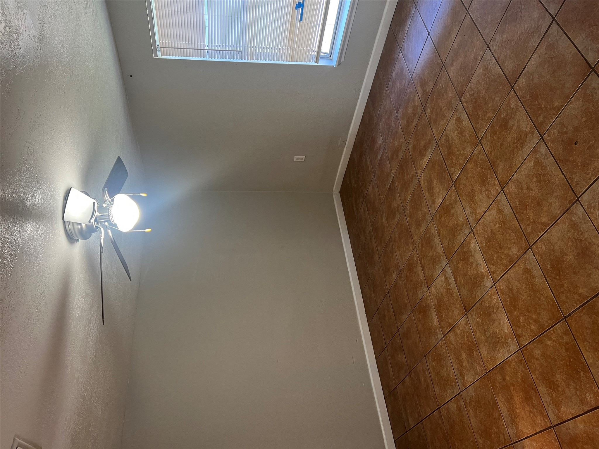 6405 Torres Street Austin, TX 78741 - Photo 6 of 14 A well-lit bedroom featuring durable tile flooring and a functional ceiling fan.