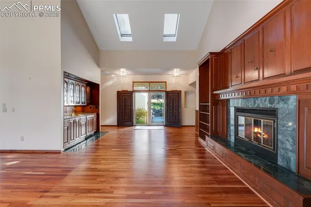 a view of an empty room with wooden floor fireplace and a window