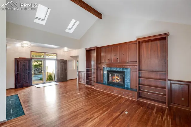 a view of an empty room with wooden floor fireplace and a window