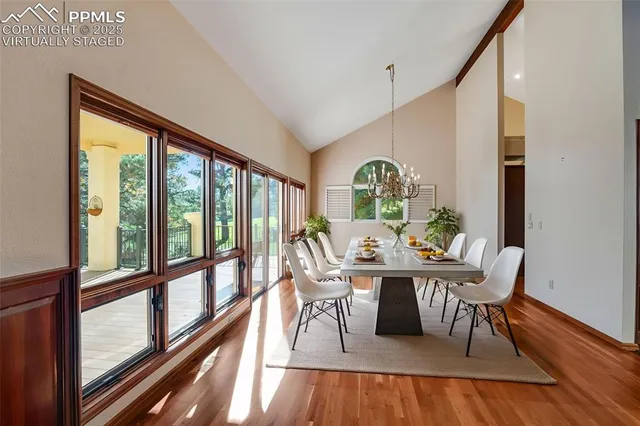 a workspace with wooden floor a glass table and windows