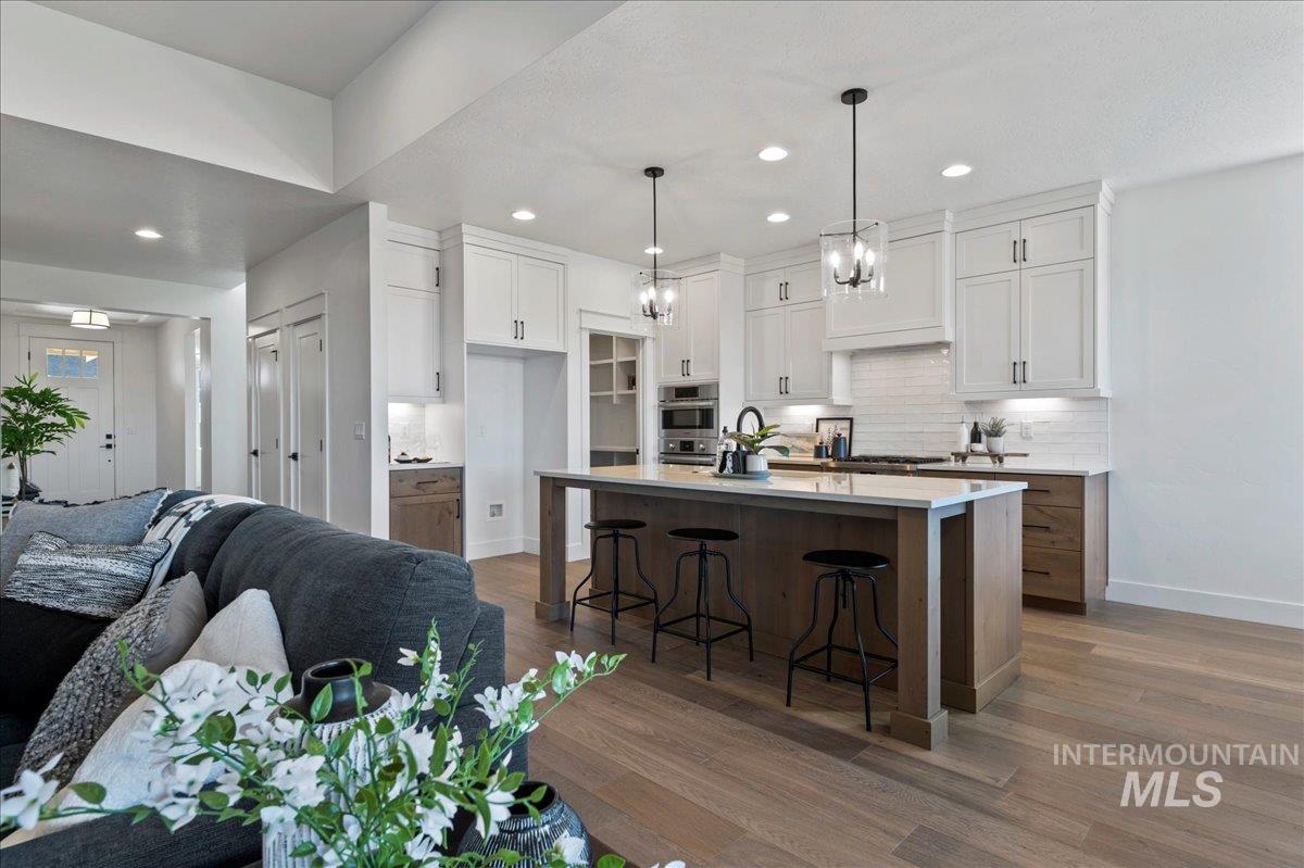 8150 West Gallup Street Meridian, ID 83646 - Photo 30 of 30 Kitchen featuring white cabinets, a breakfast bar area, open floor plan, decorative light fixtures, and dark wood-style floors