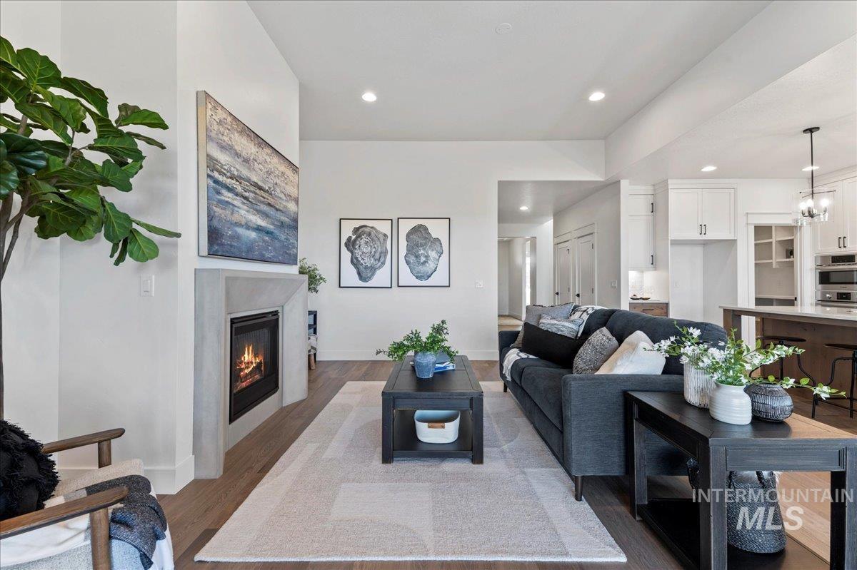 8150 West Gallup Street Meridian, ID 83646 - Photo 17 of 30 Living area featuring wood finished floors, recessed lighting, a glass covered fireplace, and a chandelier