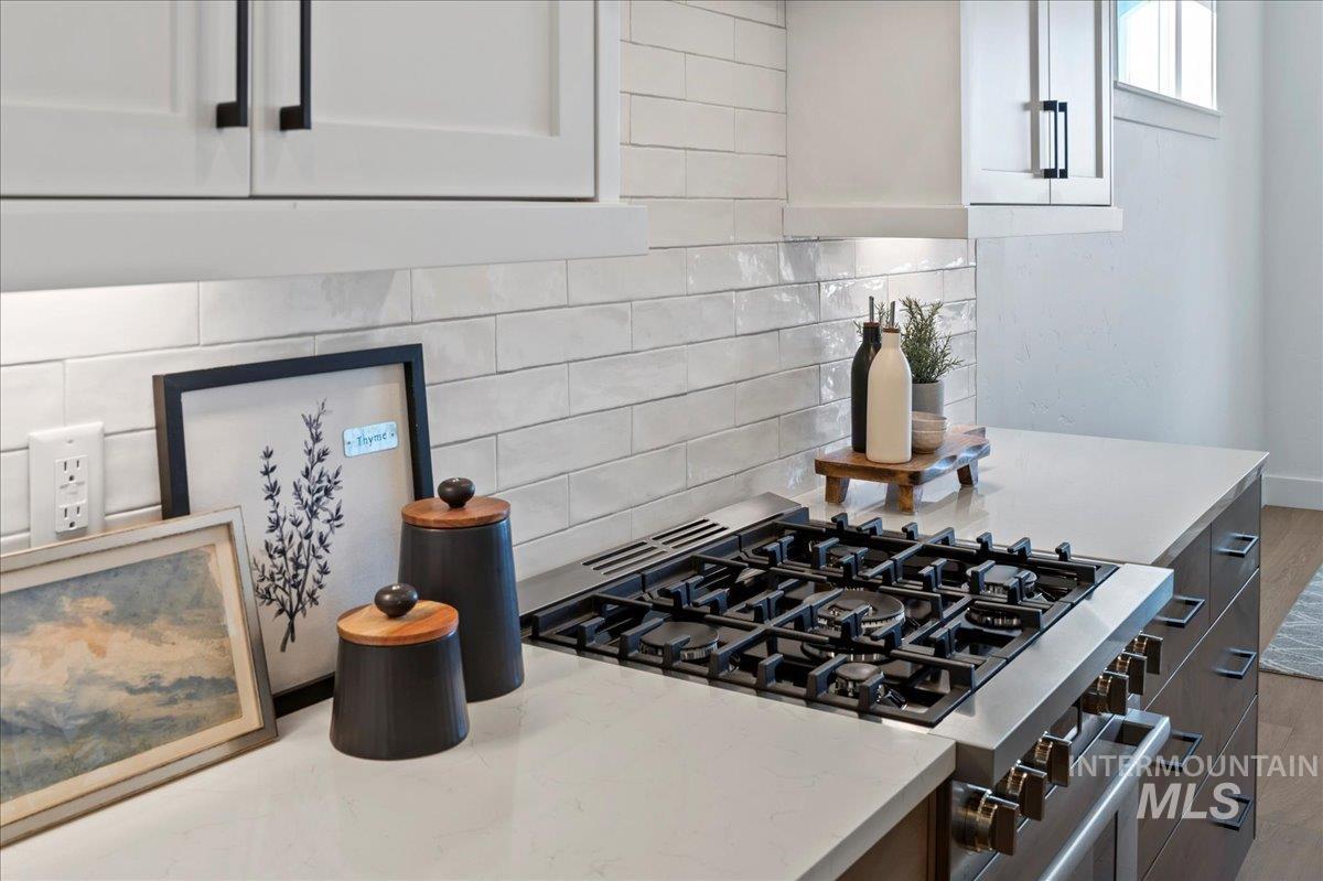 8150 West Gallup Street Meridian, ID 83646 - Photo 6 of 30 Kitchen featuring backsplash, stainless steel gas stove, white cabinetry, and light stone countertops
