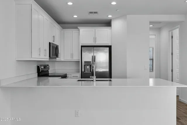 a kitchen with stainless steel appliances granite countertop a refrigerator stove a sink and white cabinets