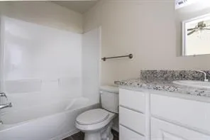 a bathroom with a granite countertop toilet a sink and a bathtub