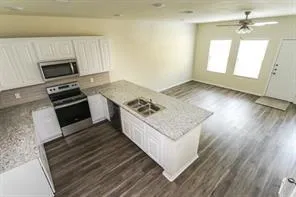 wooden floor with white cabinets and stainless steel appliances