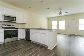 a kitchen with granite countertop a stove top oven a sink and dishwasher with wooden floor