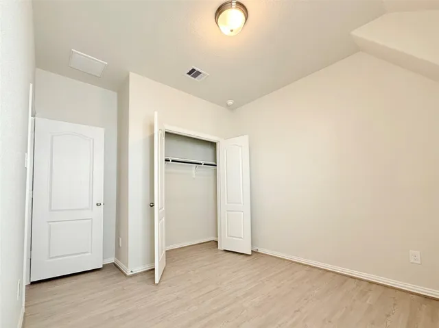 an empty room with wooden floor and closet