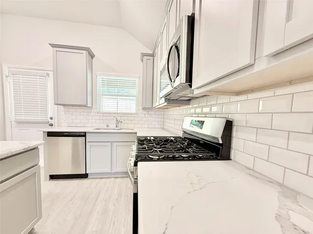 a kitchen with stainless steel appliances a stove a sink and a microwave