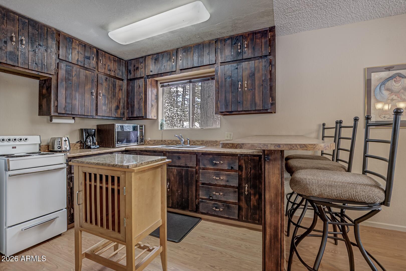 3741 Cochise Lane Pine, AZ 85544 - Photo 8 of 21 a kitchen with granite countertop a table chairs stove and cabinets
