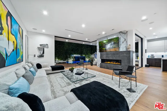 a living room with furniture a rug floor to ceiling window and a flat screen tv