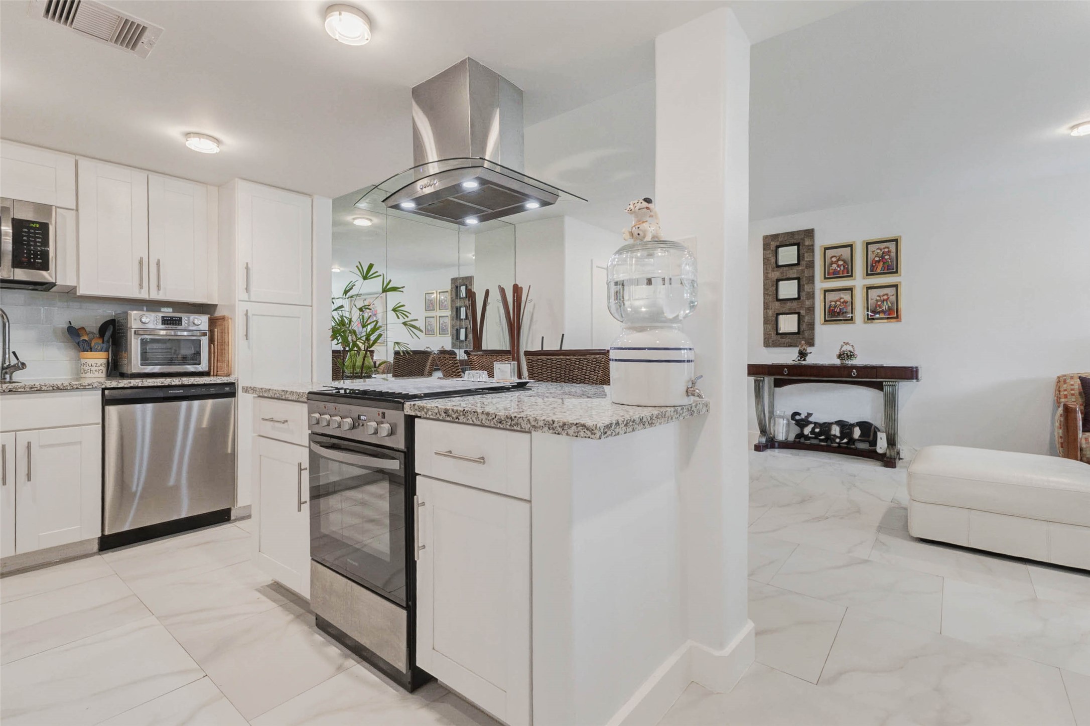 2234 South Piney Point Road, Unit 110 Houston, TX 77063 - Photo 11 of 25 Modern kitchen with sleek stainless steel appliances, granite countertops, and white cabinets. Open layout leads to a stylish living area with decorative accents, creating a bright and inviting space.