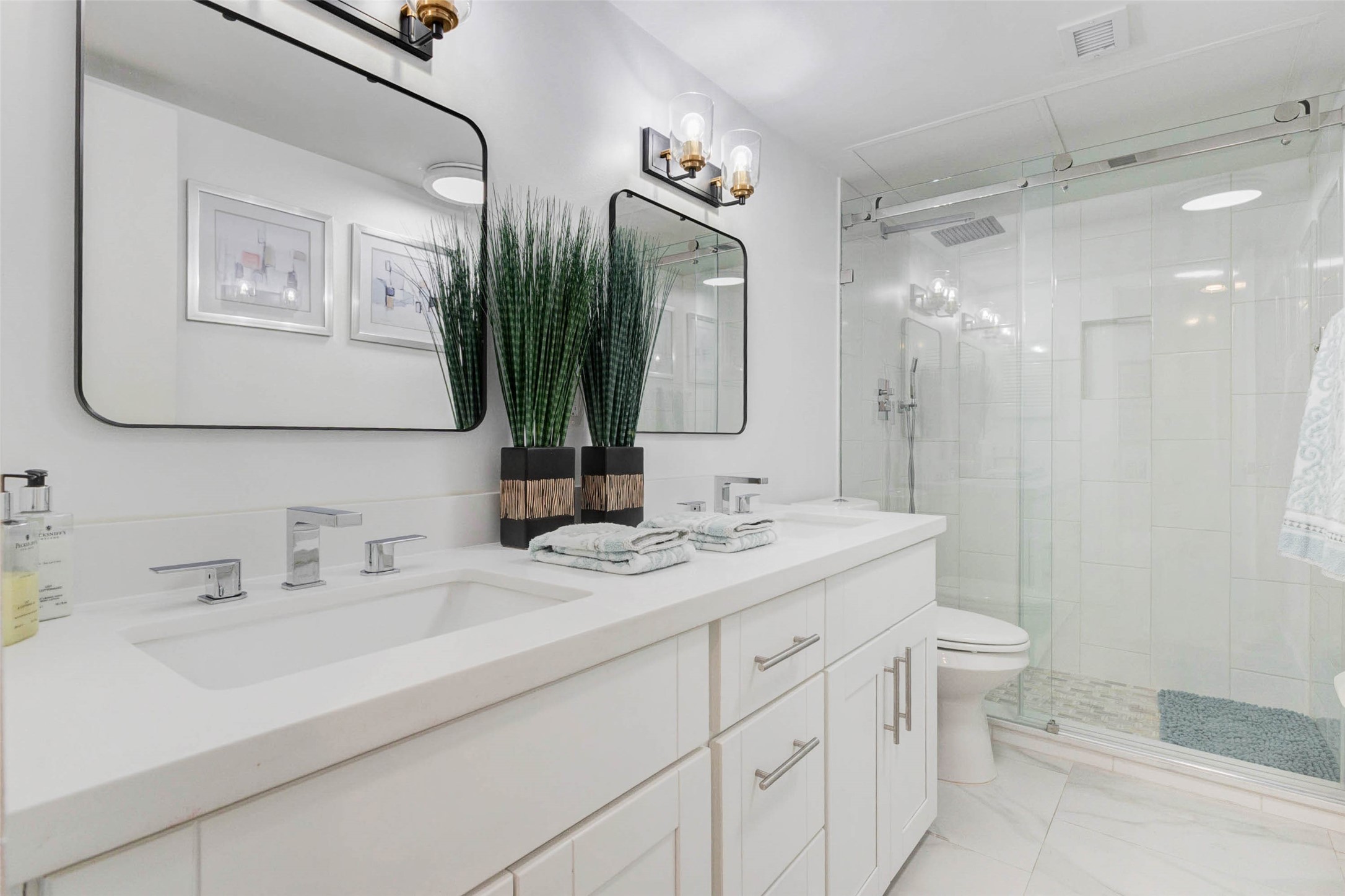 2234 South Piney Point Road, Unit 110 Houston, TX 77063 - Photo 15 of 25 This modern bathroom features a sleek double vanity with contemporary fixtures, large mirrors, and elegant lighting. It includes a spacious glass-enclosed shower and tasteful decor for a clean, sophisticated look.