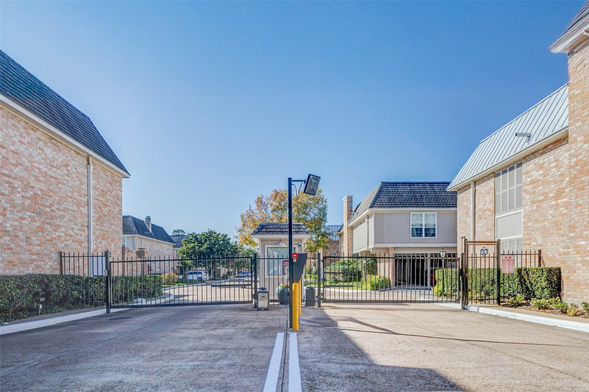 2234 South Piney Point Road, Unit 110 Houston, TX 77063 - Photo 22 of 25 Controlled access by gated entrance to a residential community with brick buildings, offering security and privacy for residents.