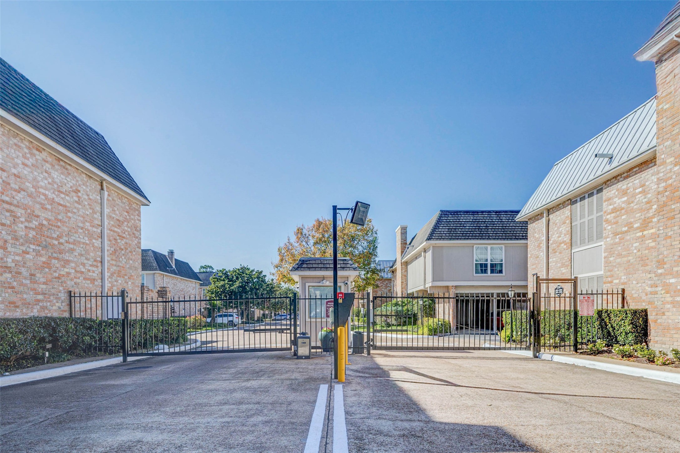 2234 South Piney Point Road, Unit 110 Houston, TX 77063 - Photo 22 of 25 Controlled access by gated entrance to a residential community with brick buildings, offering security and privacy for residents.