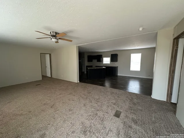 a view of an empty room and a kitchen