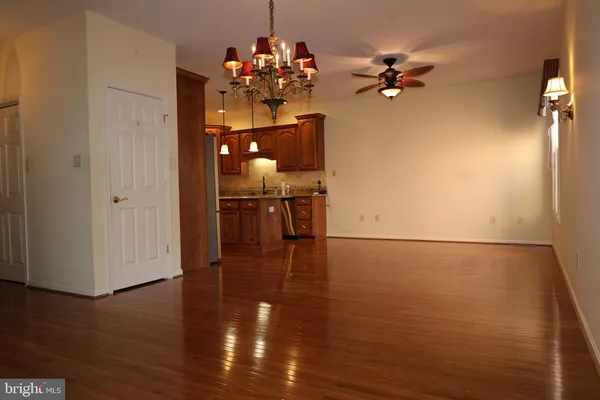 a view of a room with wooden floor chandelier and windows