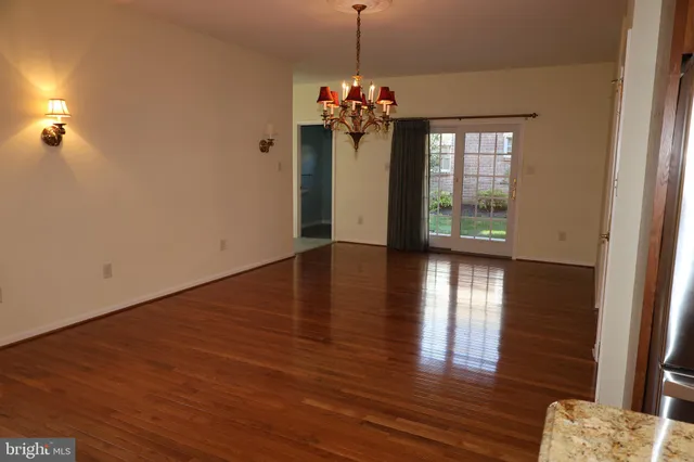 a view of a room with wooden floor chandelier and windows
