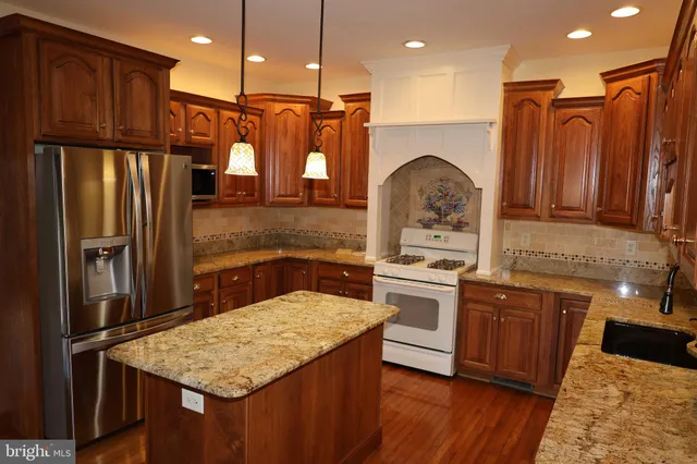 a kitchen with stainless steel appliances granite countertop a refrigerator a stove and a sink