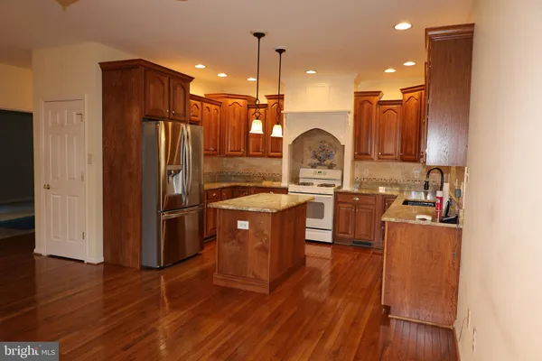 a kitchen with stainless steel appliances granite countertop a refrigerator a stove and a sink