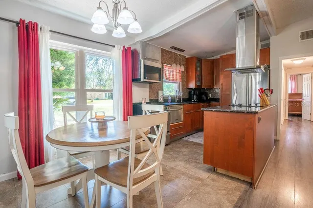 a dining room with wooden floor a chandelier a wooden table and chairs