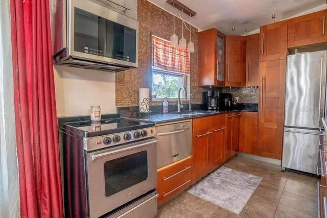 a kitchen with stainless steel appliances granite countertop a stove top oven a refrigerator and a microwave