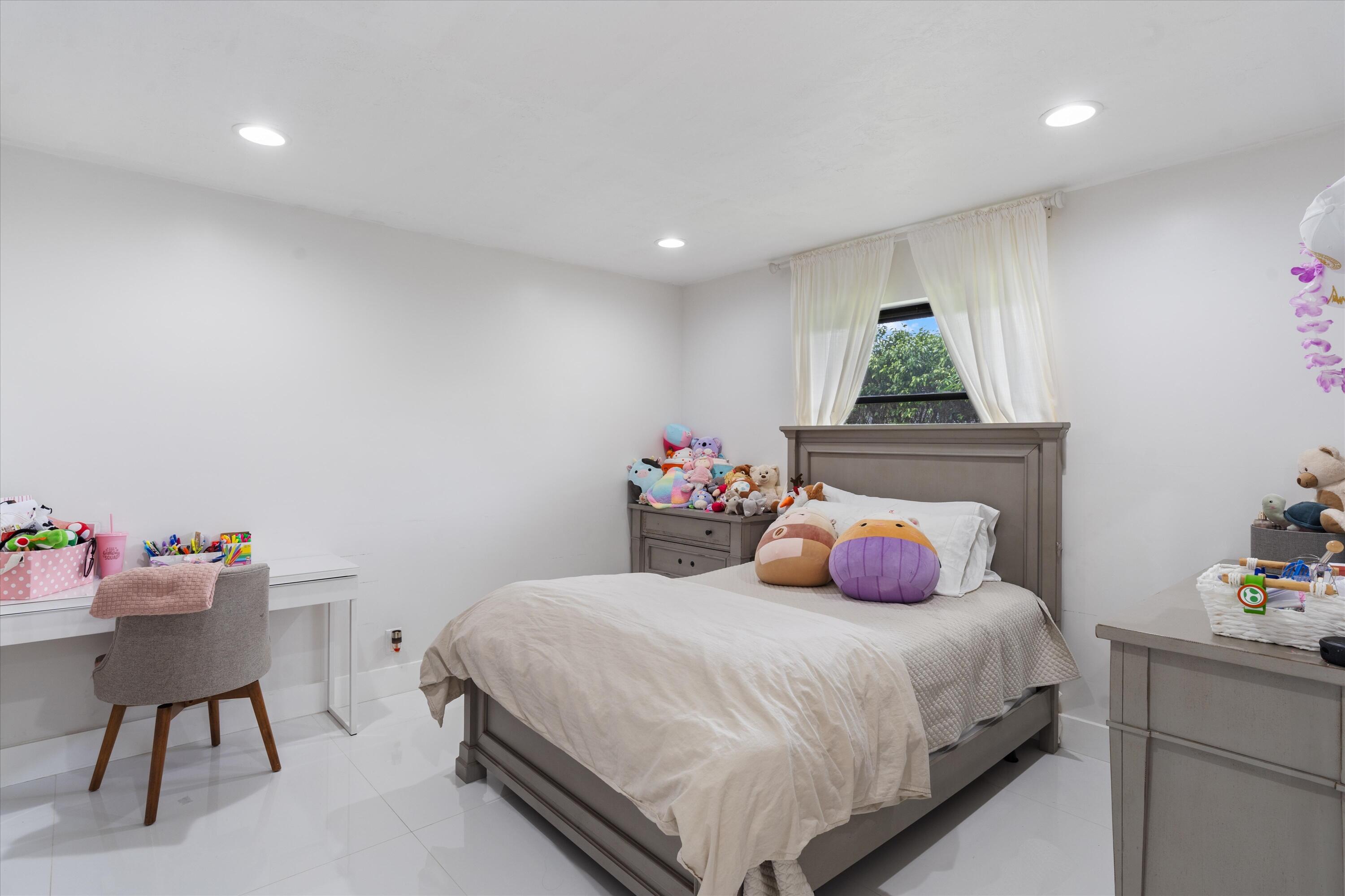 516 Muirfield Drive Atlantis, FL 33462 - Photo 19 of 43 a bedroom with a bed and a potted plant