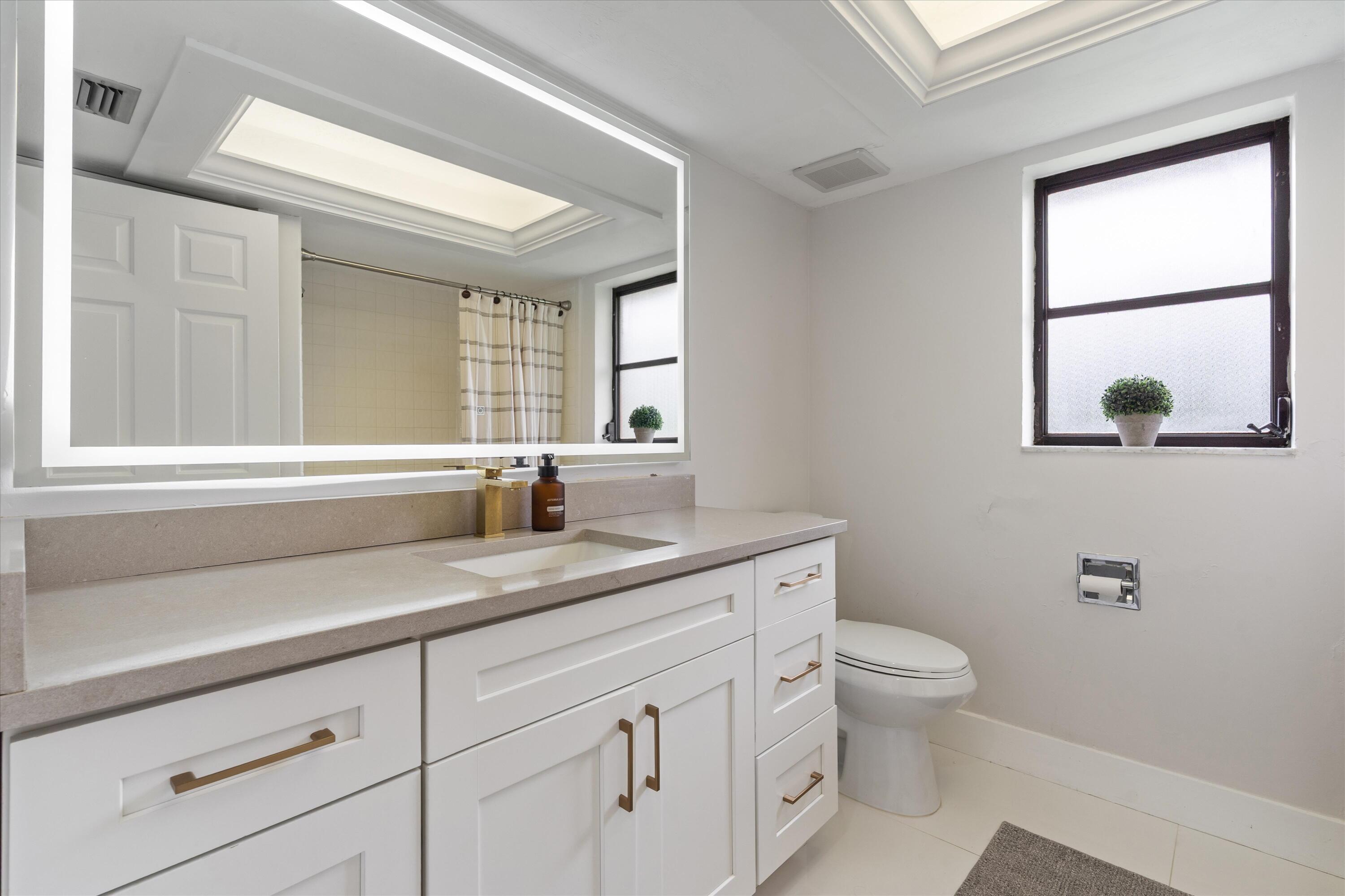 516 Muirfield Drive Atlantis, FL 33462 - Photo 20 of 43 a bathroom with a granite countertop sink a toilet and a window